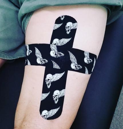 Thigh with patterned kinesiology tape applied in a cross shape