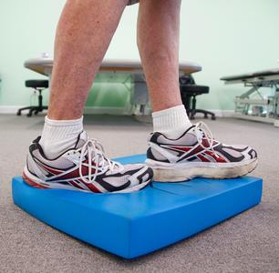 Close-up of feet standing on a blue foam balance pad
