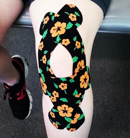 Knee with orange floral kinesiology tape applied